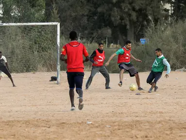 Sejumlah pria bermain sepak bola di lapangan tanah sebelum buka puasa selama bulan Ramadhan, di ibu kota Libya, Tripoli (24/4/2021). (AFP/Mahmud Turkia)