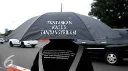 Seorang aktivis Solidaritas Korban untuk Keadilan membawa payung yang bertuliskan seruan aksinya saat menggelar aksi Kamisan di depan Istana Merdeka, Jakarta, Kamis (29/12). (Liputan6.com/Gempur M Surya)