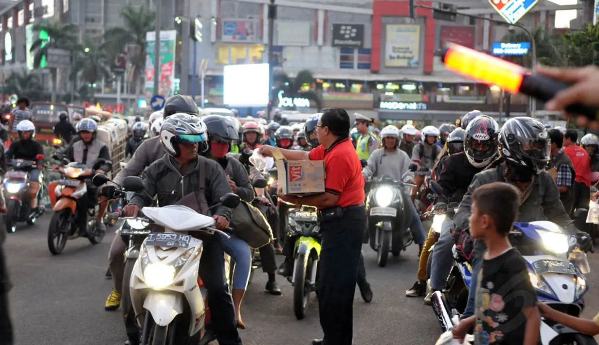 Seorang relawan tampak membagikan takjil di tengah padatnya arus lalu lintas, Jakarta, Kamis (24/7/14). (Liputan6.com/Panji Diksana)