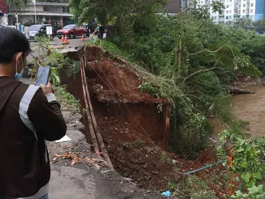 Warga melihat Lokasi longsor di daerah bantaran sungai Ciliwung, Pengadegan Timur, Jakarta, Selasa (12/4/2022). Longsor sepanjang 25 meter, lebar lima meter, dan kedalaman 15 meter itu menyebabkan 4 sepeda motor tertimbun material longsor, namun tidak ada korban jiwa. (Liputan6.com/Herman Zakharia)
