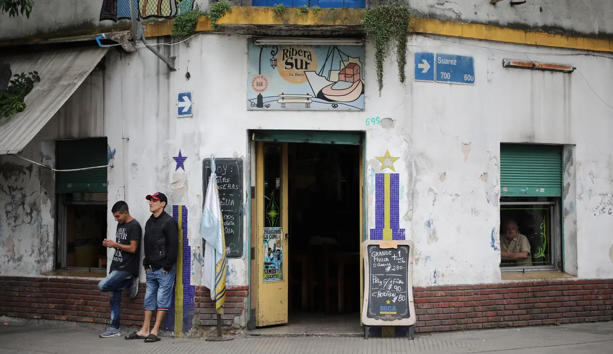 Dua orang pria berdiri di luar restoran Ribera Sur di lingkungan La Boca, ibu kota Argentina, Buenos Aires pada 27 November 2018. La Boca merupakan salah satu pusat kebudayaan dan wisata di Buenos Aires. (Ludovic MARIN / AFP)