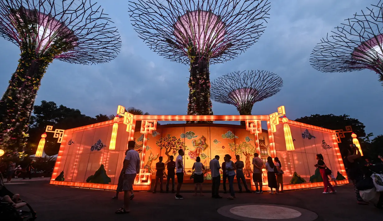 Pengunjung melihat lentera yang berputar selama pratinjau media untuk Mid-Autumn Festival di Gardens by the Bay, Singapura, Selasa (27/8/2019). Festival ini sebagai penanda berakhirnya panen musim gugur, atau Mid-Autumn sekaligus momen untuk memanjatkan syukur kepada dewa-dewi. (Roslan RAHMAN/AFP)