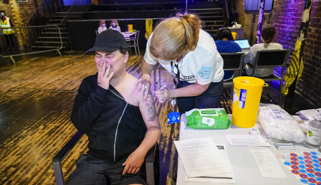 Drag queen Baga Chips disuntik vaksin Pfizer di pop-up pusat vaksinasi Covid yang didirikan di klub malam Heaven di London, Minggu (8/8/2021). Heaven menjadi klub malam pertama di Inggris yang diubah sebagai pop-up pusat vaksinasi untuk mengajak kaum muda agar mau divaksin (AP/Alberto Pezzali)