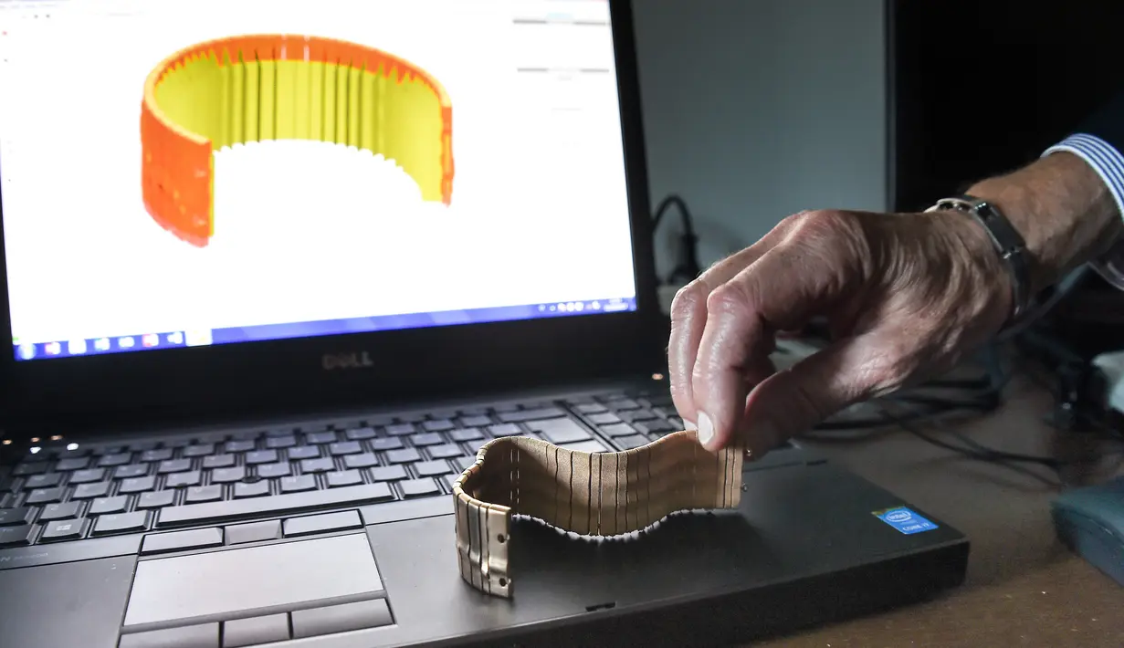 Seorang pekerja Comite Franceclat memperlihatkan gelang emas hasil mesin cetak 3D di Besancon, Prancis, 11 Oktober 2017. Mesin cetak 3D kini mulai merambah ke dunia desain perhiasan. (AFP FOTO / SEBASTIEN BOZON)