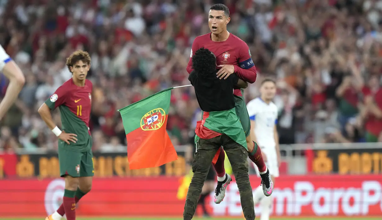 Seorang penyusup lapangan mengangkat striker Timnas Portugal, Cristiano Ronaldo di tengah laga Grup J Kualifikasi Euro 2024 antara Timnas Portugal menghadapi Bosnia Herzegovina di Luz Stadum, Lisbon, Portugal, Minggu (18/6/2023) dini hari WIB. (AP Photo/Armando Franca)