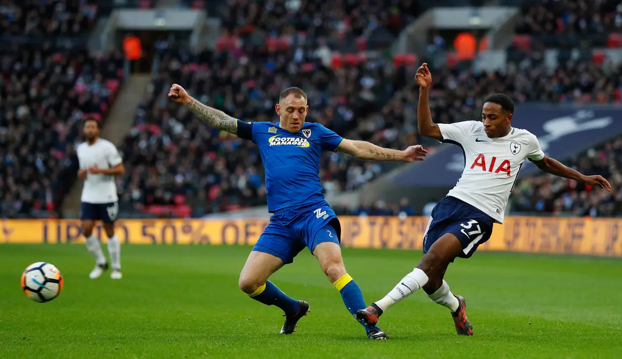 Pemain Wimbledon Barry Fuller memblokir tendangan bek Tottenham Hotspur Kyle Walker-Peters pada pertandingan putaran ketiga FA Cup di Stadion Wembley, Minggu (7/1). Tottenham Hotspur menyarangkan tiga gol ke gawang Wimbledon. (Adrian DENNIS/AFP)