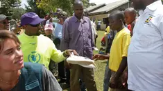 Rapper AS, Kanye West memberikan sepatu kets kepada seorang anak saat mengunjungi Kampung Anak UWESCO di Masulita, Uganda, Selasa (16/10). Kanye West membagikan ratusan pasang Yeezy Boost 350 V2s kepada anak-anak yatim piatu di sana. (AP/Stephen Wandera)