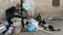 Georges Gerges, yang dijuluki "Kapten" memberi makan kucing di sudut jalan kawasan industri Dora di pinggiran utara Beirut, Lebanon, Rabu (8/11). Dengan tubuh yang terlihat lusuh, Gerges kini menghabiskan masa senjanya di jalanan. (JOSEPH EID/AFP)