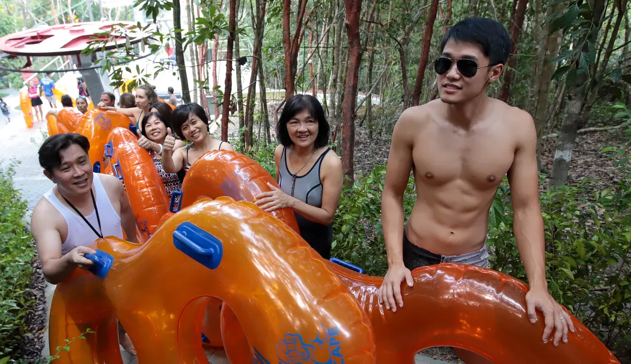 Pengunjung membawa pelampung bersiap menaiki perosotan air terpanjang di dunia di Escape theme park di Teluk Bahang, Malaysia (25/9/2019). Pengunjung diajak menuruni lereng setinggi 70 meter melintasi hutan dan pepohonan saat berada di perosotan air ini. (AFP Photo/Sadiq Asyraf)
