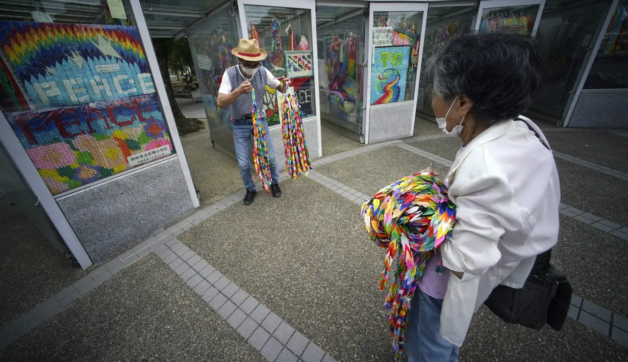 Hatsue Onda (kanan) dan Kengo Onda menawarkan ribuan origami kepada para korban bom atom 1945 di dekat Museum Peringatan Perdamaian Hiroshima, Hiroshima, Jepang, Senin (3/8/2020). Jepang akan memperingati 75 tahun bom atom di Hiroshima pada 6 Agustus 2020. (AP Photo/Eugene Hoshiko)