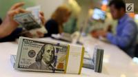 Petugas bank menghitung uang dollar AS di Jakarta, Jumat (20/10). Nilai tukar Rupiah terhadap Dolar Amerika Serikat (USD) masih belum beranjak dari level Rp 13.500-an per USD. (Liputan6.com/Angga Yuniar)