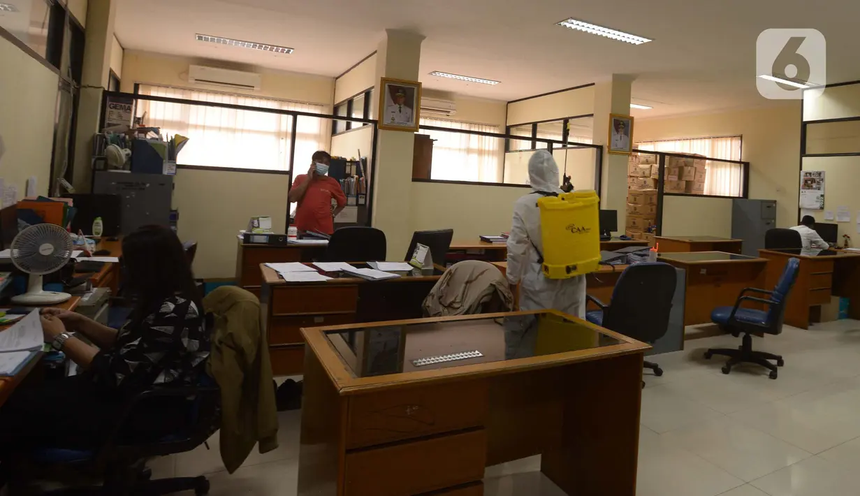 Petugas menyemprotkan cairan disinfektan di ruang kerja dan ruang pelayanan Suku Dinas Sosial Jakarta Timur, Jumat (18/2/2022). Sebanyak 6 orang yang terpapar Covid-19 sedang menjalani isolasi di rumah, sementara pelayanan ditutup selama tiga hari. (merdeka.com/Imam Buhori)