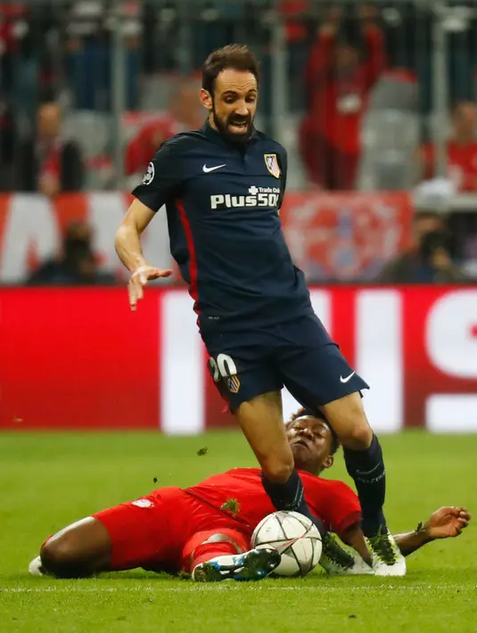 Bek Atletico Madrid, Juanfran berusaha membawa bola dari kawalan bek Muenchen, David Alaba di semifinal Liga Champions di Allianz Arena (4/5). Meski kalah 2-1 dari Munchen, Atletico melaju ke final dengan aggregat gol tandang. (Reuters/Kai Pfaffenbach)
