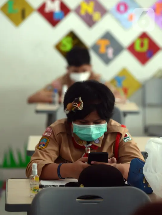 Seorang murid melihat gawai saat mengikuti uji coba pembelajaran tatap muka di SDN Malaka Jaya 07 Jakarta, Rabu (9/6/2021). Sebanyak 226 sekolah yang telah mengikuti proses asesmen dan evaluasi sejak 24 Mei - 4 Juni 2021 melaksanakan uji coba pembelajaran tatap muka. (merdeka.com/Imam Buhori)