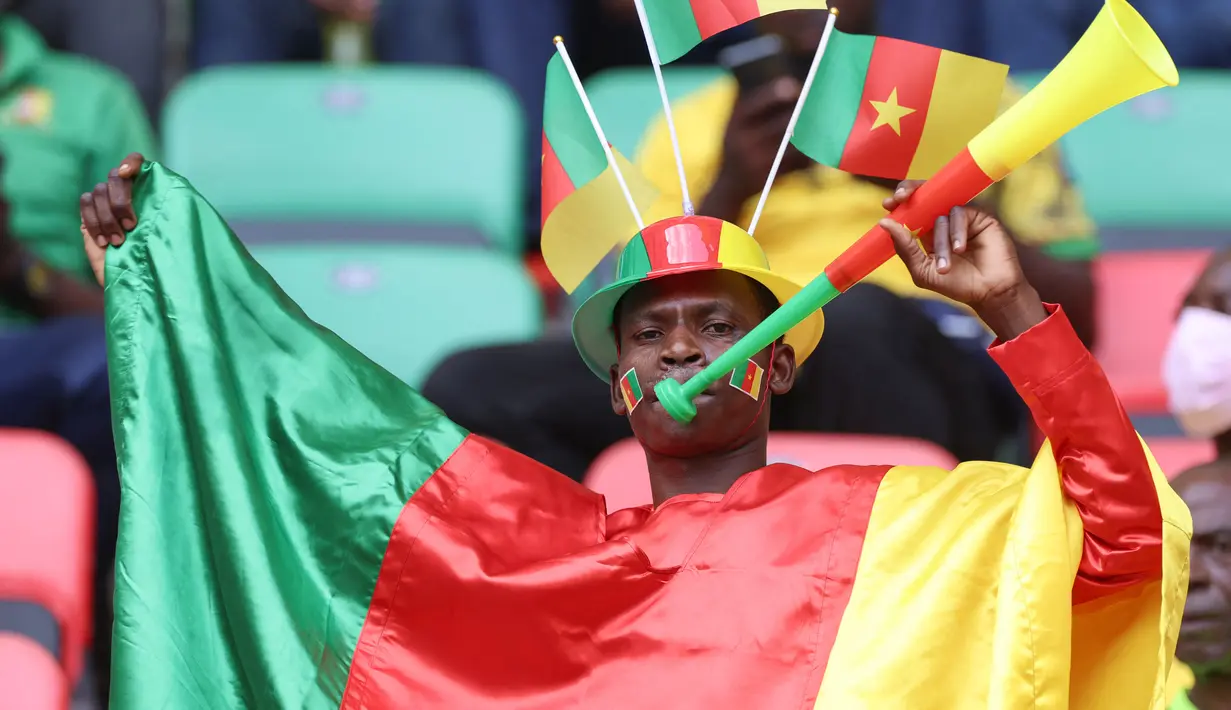 Seorang Suporter Kamerun meniup terompet sambil bersorak menjelang upacara pembukaan turnamen Piala Afrika (CAN) 2021 di Stade d'Olembé di Yaounde (9/1/2022). Kamerun untuk kali kedua menjadi tuan rumah Piala Afrika setelah pada 1972. (AFP/Kenzo Tribouillard)