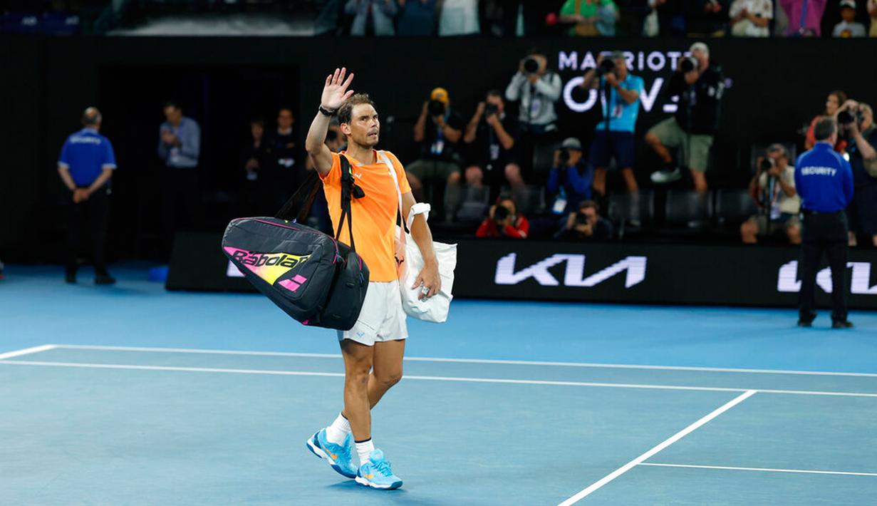 Petenis Spanyol Rafael Nadal melambaikan tangan saat meninggalkan Rod Laver Arena menyusul kekalahannya atas petenis Amerika Serikat Mackenzie McDonald pada pertandingan putaran kedua kejuaraan tenis Australian Open di Melbourne, Australia, Rabu (18/1/2023). Rafael Nadal harus tersingkir dari Australian Open 2023 setelah ia mengalami cedera dan kemudian takluk 4-6, 4-6, 5-7 dari petenis Amerika Serikat MacKenzie McDonald. (AP Photo/Asanka Brendon Ratnayake)