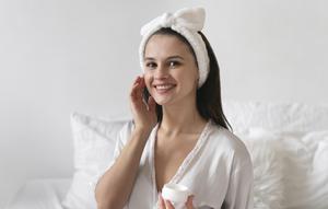 Seorang perempuan sedang mengaplikasikan skincare ke wajahnya (Foto Dok: Freepik/freepik).