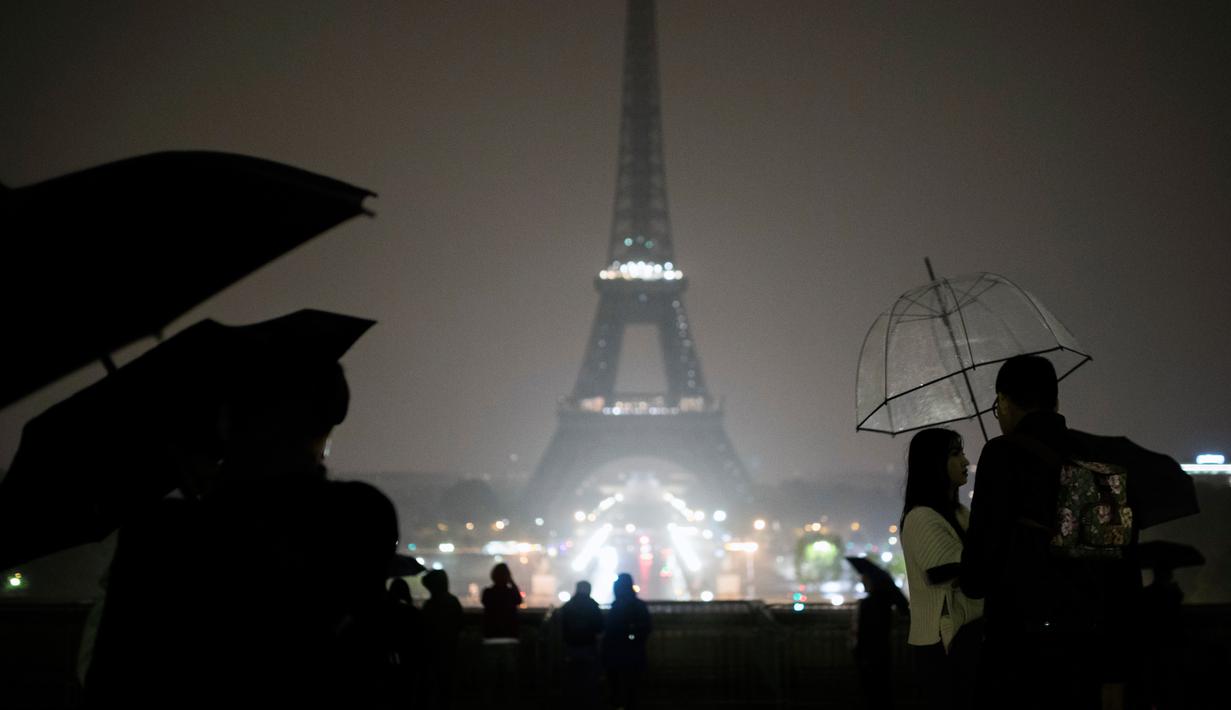Pengunjung berkumpul di alun-alun Trocadero ketika lampu Menara Eiffel dipadamkan di Paris, Senin (2/10). Pemadaman lampu menara yang menjadi ikon Negara Prancis ini sebagai bentuk penghormatan untuk korban penembakan di Las Vegas. (AP/Kamil Zihnioglu)