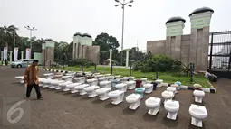 Seorang pria melintas di depan puluhan jamban yang di letakkan di depan gedung DPR RI, Jakarta, Kamis (3/12). Aksi yang dinamakan “Aksi Djamban DPR” ini menyindir kasus “Papa Minta Saham” yang dilakukan Setya Novanto. (Liputan6.com/Immanuel Antonius)
