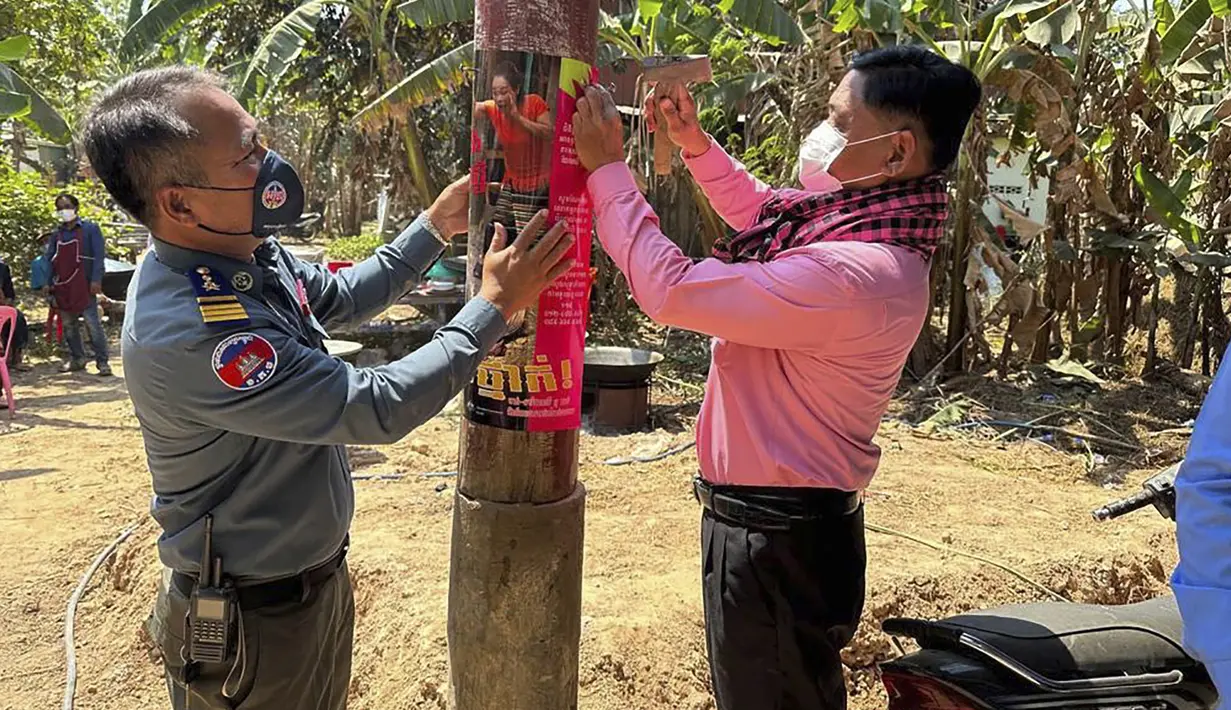 <p>Dalam foto yang dirilis oleh Kementerian Kesehatan Kamboja ini, seorang petugas kesehatan hewan Kamboja, kanan, dan seorang perwira polisi militer memasang poster tentang kesadaran akan ancaman virus H5N1 dengan harapan dapat mengedukasi penduduk desa untuk menjaga kesehatan mereka, di Prey Veng, Kamis (23/2/2023). Seorang anak perempuan berusia 11 tahun di Kamboja meninggal karena flu burung dalam infeksi H5N1 manusia pertama yang diketahui di negara itu sejak 2014, kata pejabat kesehatan. (Cambodia Ministry of Health via AP)</p>