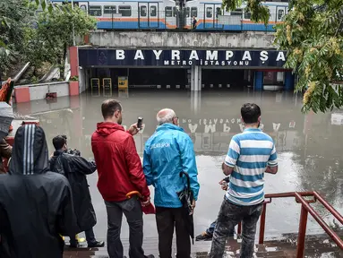 Sejumlah orang mengambil gambar stasiun metro Bayrampasa yang terendam banjir di kota Istanbul, Turki, Selasa (18/7). Banjir cukup parah akibat diguyur hujan lebat selama 12 jam ini merendam sejumlah wilayah di Istanbul. (OZAN KOSE / AFP)