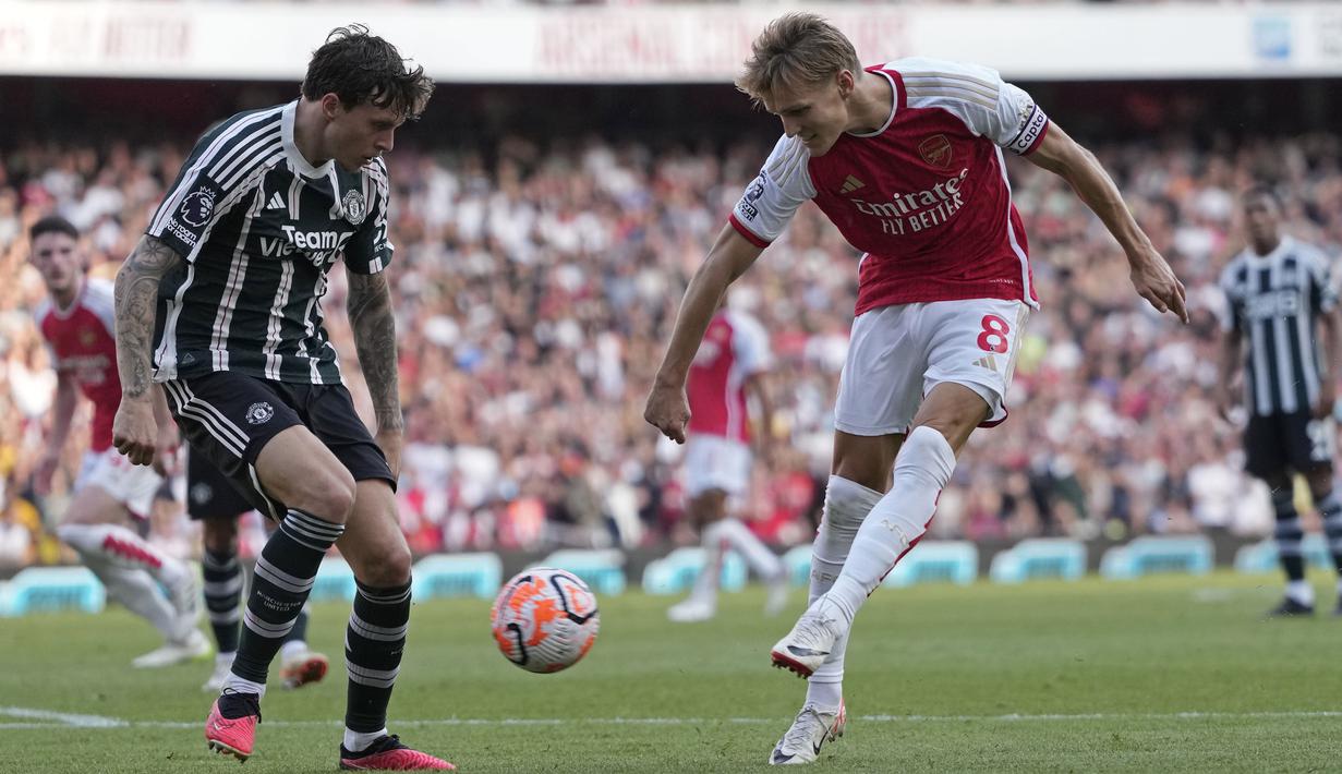 Martin Odegaard (kanan), menendang bola ke gawang MU yang membuahkan gol pertama bagi Arsenal dalam pertandingan lanjutan Liga Inggris 2023/2024 yang berlangsung di Emirates Stadium, London, Minggu (3/9/2023) malam WIB. (AP Photo/Kirsty Wigglesworth)