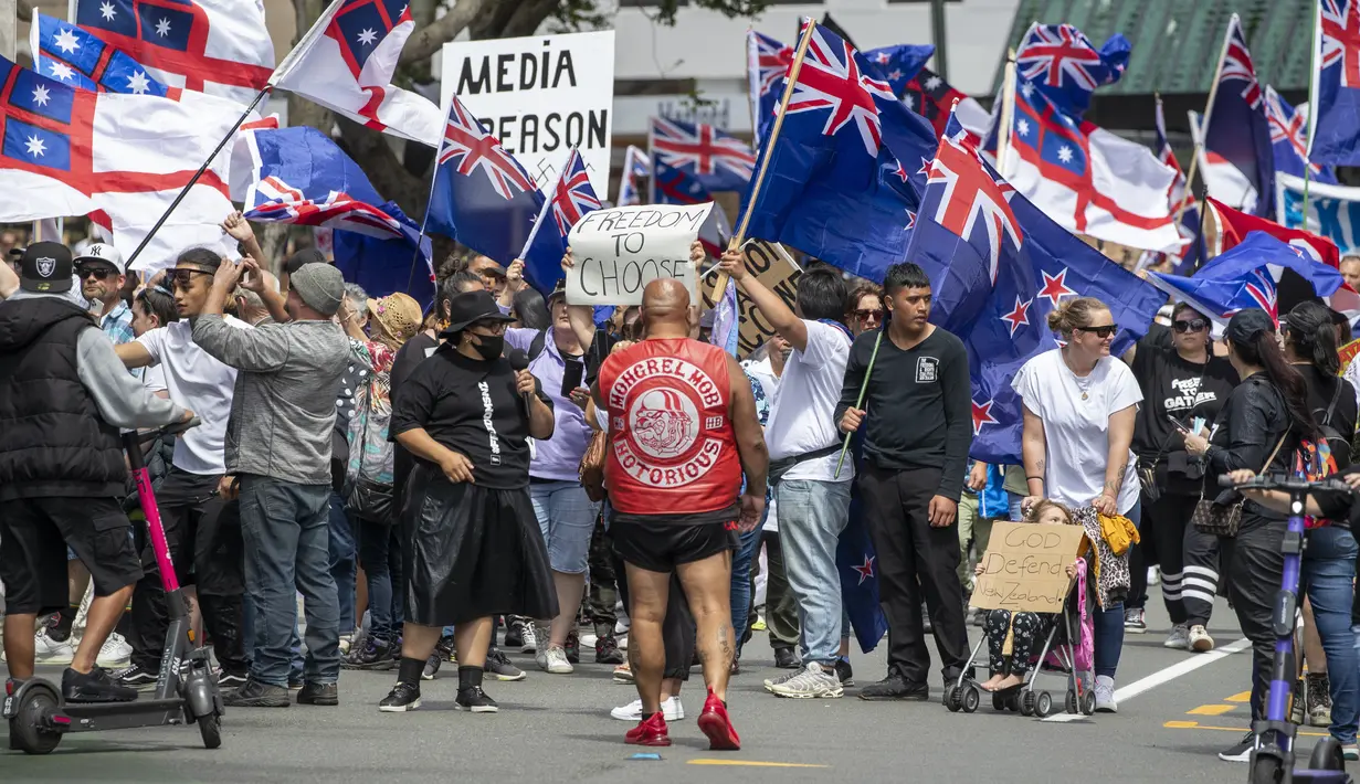 Demonstran berbaris di sepanjang Lambton Quay sebelum berkumpul di gedung Parlemen Selandia Baru, di Wellington, Selasa (9/11/2021). Ribuan warga Selandia Baru berdemonstrasi memprotes kebijakan vaksin covid-19 dan penguncian (lockdown) yang diterapkan negara itu. (Mark Mitchell/NZ Herald via AP)