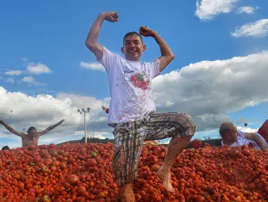 Peserta berdiri di atas gundukan tomat saat Festival Tomatina di Sutamarchan, Boyaca, Kolombia, Minggu (2/6/2019). Perang tomat ini digelar selama tiga hari berturut-turut. (Diana SANCHEZ/AFP)