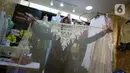 Penjahit menunjukkan pakaian di Pasar Mayestik, Jakarta, Selasa (11/5/2021). Menjelang Lebaran, pesanan jahitan turun sebesar 50 persen akibat pandemi COVID-19 serta larangan pemerintah terkait mudik luar kota dan mudik lokal. (Liputan6.com/Faizal Fanani)