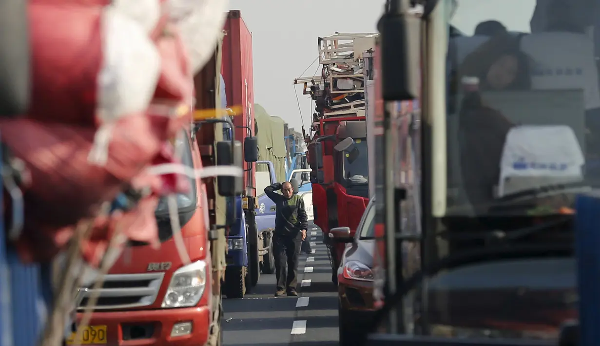 Seorang pria berjalan di antara kendaraan yang terjebak kemacetan parah di Jinji Expressway, antara Beijing-Tianjin, China, Rabu (2/3). (REUTERS/Kim Kyung - Hoon)