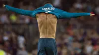 Pemain Real Madrid, Cristiano Ronaldo mengenakan kembali jerseynya seusai melakukan selebrasi di hadapan suporter Camp Nou pada leg pertama Piala Super Spanyol, Senin (14/8). Laga itu berakhir dengan skor 3-2 bagi Barcelona. (STRINGER/AFP)