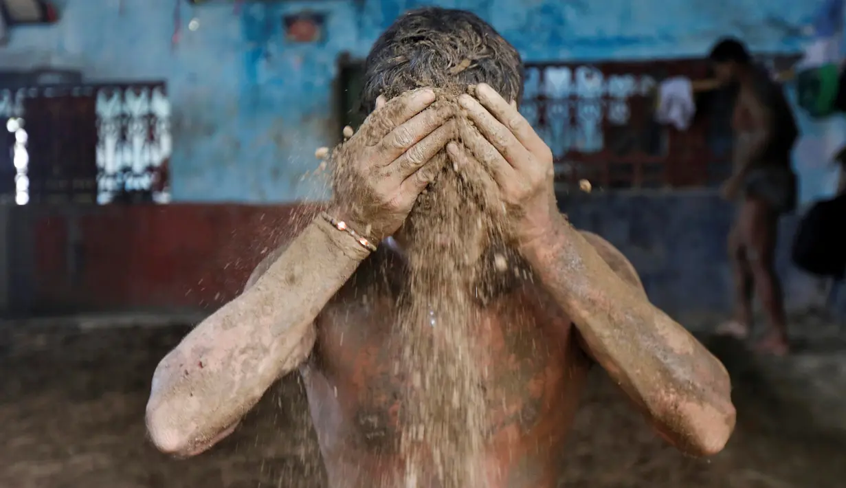 Seorang pegulat menaburkan lumpur ketubuhnya agar tidak terjatuh karena berkeringat saat berlatih di pusat pelatihan tradisional di tepi Sungai Gangga menjelang Bengal kejuaraan gulat lumpur, di Kolkata, India 17 Mei 2016. (REUTERS/Rupak De Chowdhuri)