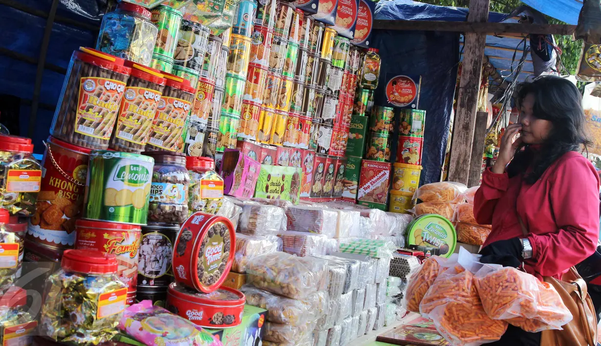 Pengunjung memilih kue kaleng di kios penjual kue kering musiman di kawasan Ciracas, Jakarta, Minggu (12/7). Sejak beberapa hari terakhir, transaksi pedagang musiman kue kering mengalami peningkatan jelang hari raya Idul Fitri. (Liputan6.com/Helmi Afandi)
