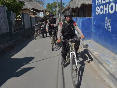 Polisi bersepeda berpatroli di kawasan wisata Pulau Gili Air, Lombok, Nusa Tenggara Barat (NTB), Sabtu (11/8). Patroli dilakukan setelah gempa 7 skala Richter melanda Lombok pada 5 Agustus lalu. (Adek BERRY/AFP)