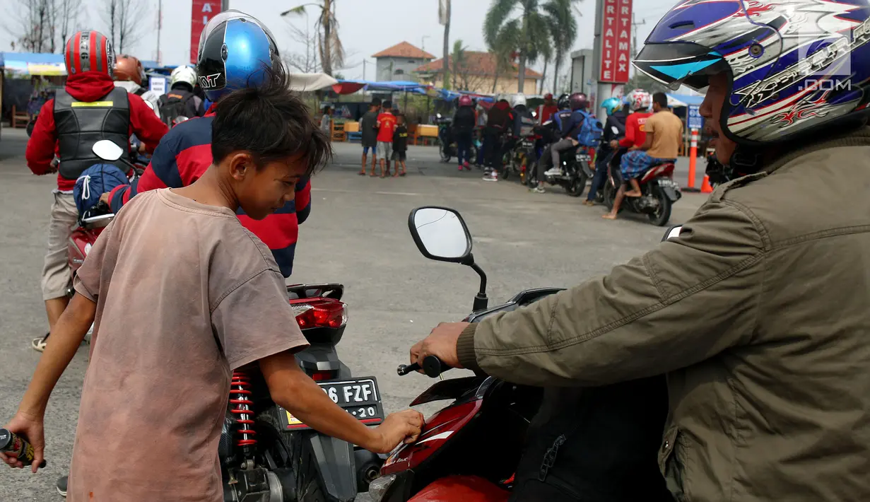 Seorang anak membersihkan motor yang di kendarai pemudik dari Jakarta menuju kampung halamannya di SPBU Tanjung Pantura - Brebes, Kamis (22/6). Memanfaatkan moment mudik anak - anak pantura mengais rejeki untuk lebaran 1438 H. (Liputan6.com/Johan Tallo)