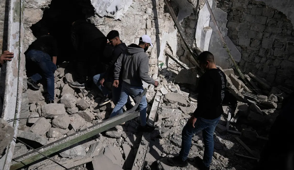 Warga Palestina memeriksa reruntuhan tempat persembunyian militan yang dihancurkan selama serangan oleh pasukan Israel di Kota Nablus, Tepi Barat, 22 Februari 2023. Pemuda Palestina melempari kendaraan pengangkut pasukan lapis baja dengan batu. (AP Photo/Majdi Mohammed)