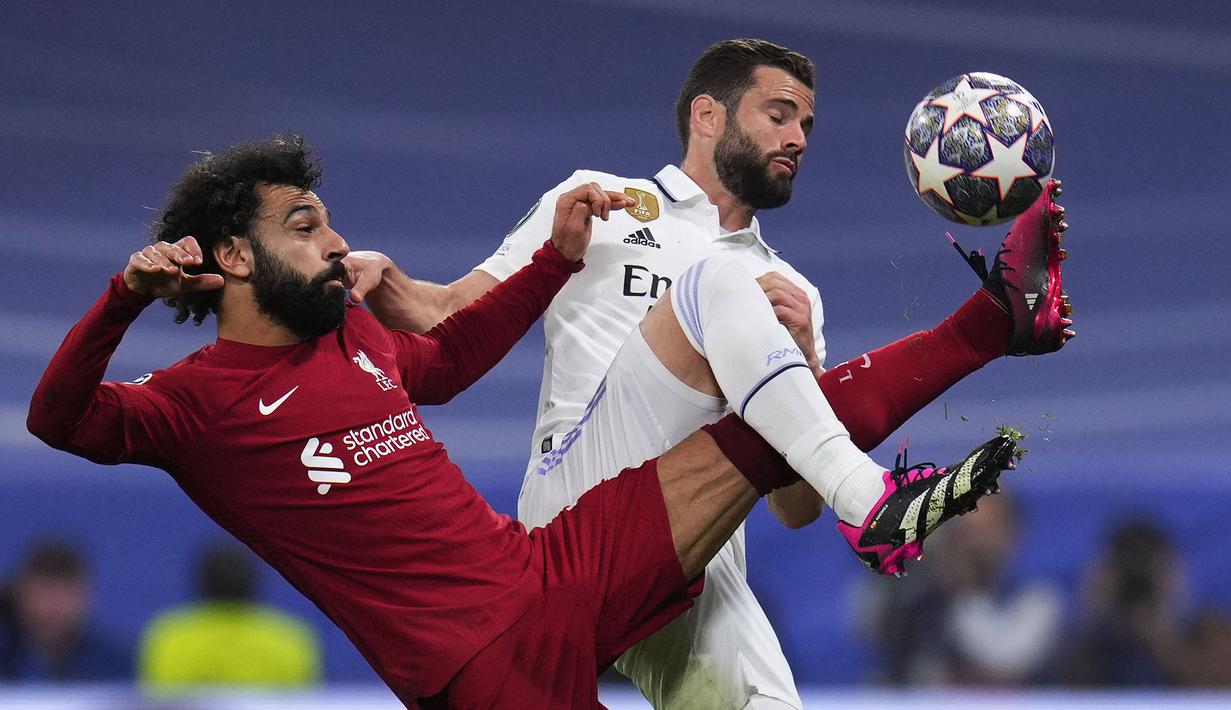 <p>Pemain Liverpol, Mohamed Salah (kiri) berebut bola dengan pemain Real Madrid, Nacho pada laga 16 besar Liga Champions 2022/2023 yang berlangsung di Santiago Bernabeu, Madrid, Spanyol, Kamis (16/03/2023) WIB. Laga dimenangkan oleh Real Madrid dengan skor 1-0. (AP Photo/Manu Fernandez)</p>