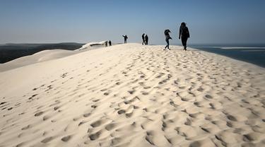 Orang-orang menikmati hari yang cerah di "Dune du Pilat" di La Teste-de-Buch, dekat Teluk Arcachon di barat daya Prancis pada 3 April 2021. The Dune of Pilat merupakan gurun pasir tertinggi di Eropa, yaitu sekitar 110 meter di atas permukaan air laut. (Philippe LOPEZ / AFP)
