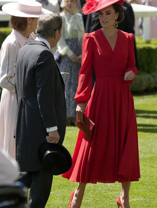 <p>Kate juga memadukan gaunnya dengan clutch bag merah dari Hermes dan sepatu pump suede merah.(AP Photo/Alastair Grant)</p>
