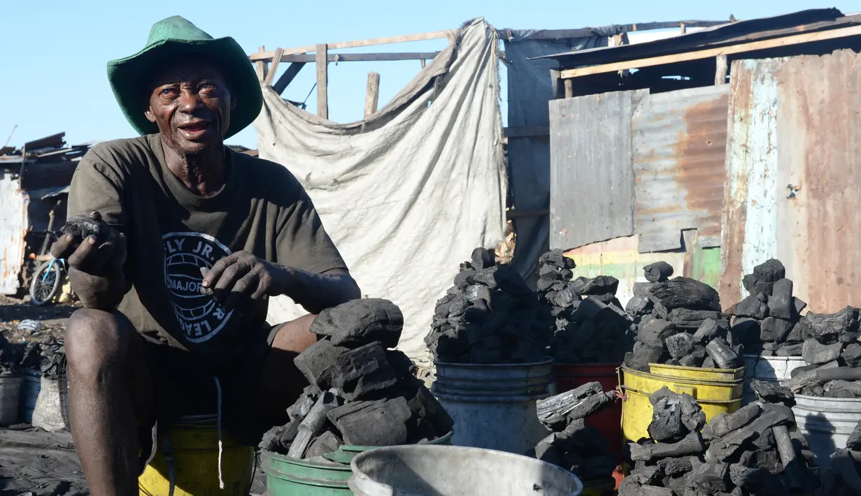 Seorang penjual arang menunjukan dagangannya di pasar sentral Les Cayes, Haiti, (25/1). Menteri Lingkungan Hidup Haiti akan membuat peraturan jaringan "hutan energi" yang menghasilkan kayu untuk arang dan kayu bakar. (AP/David McFadden)