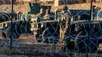 Tentara Pengawal Nasional Texas berjaga di belakang kawat berduri di perbatasan AS-Meksiko, Ciudad Juarez, Meksiko, Rabu (21/12/2022). Kebijakan Judul 42 ini dilakukan Trump untuk menghentikan penyebaran virus Corona dan memungkinkan AS mengusir hampir semua orang yang tertangkap melewati perbatasan secara ilegal. (JOHN MOORE / GETTY IMAGES NORTH AMERICA / Getty Images via AFP)