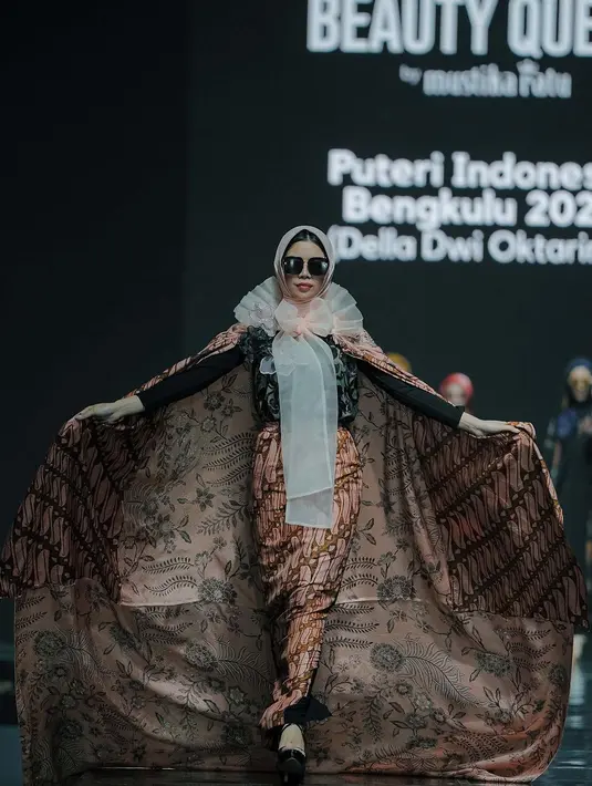 Della Oktarina tampil nyetrik dengan atasan dan rok batik panjang. Outfitnya disempurnakan dengan kerudung dan cape batik serta aksen tulle yang manis. [@officialputeriindonesia]