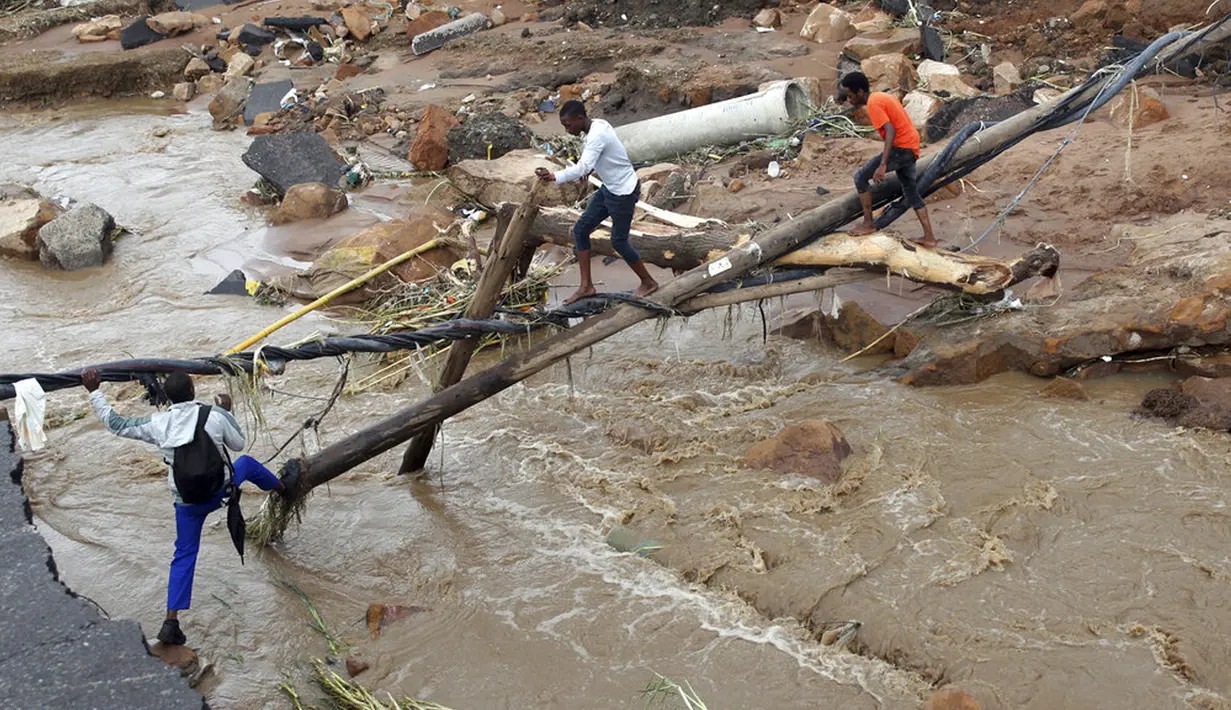 Warga berjalan melintasi jembatan darurat di atas sungai setelah sebuah jembatan hanyut di Ntuzuma, luar Durban, Afrika Selatan, 12 April 2022. Hujan berkepanjangan dan banjir di Provinsi KwaZulu-Natal Afrika Selatan telah merenggut nyawa setidaknya 20 orang, menurut pejabat setempat. (AP Photo/Str)