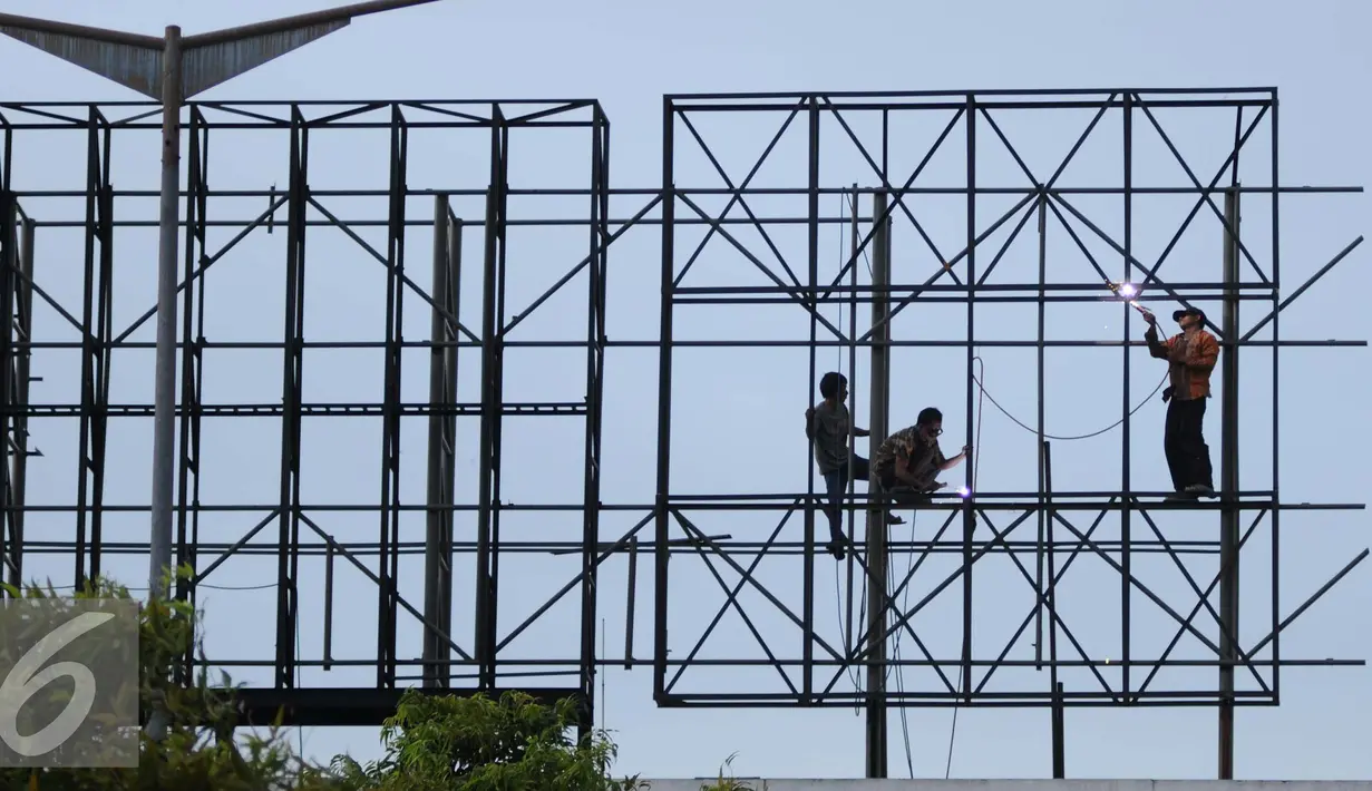 Pekerja menyelesaikan pembuatan papan reklame di jalan Gadjah Mada, Jakarta, Selasa (13/12). Pemerintah DKI Jakarta akan menyusun rencana penataan terhadap reklame yang tidak beraturan di jalur protokol. (Liputan6.com/Gempur M. Surya)