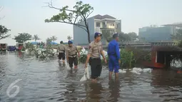 Petugas dibantu warga membetulkan  tanggul yang jebol di kawasan Perumahan Pantai Mutiara, Jakarta, Sabtu (4/6). Akibat tanggul jebol kawasan tersebut tergenang dengan ketinggian 50-60 sentimeter. (Liputan6.com/Gempur M Surya)