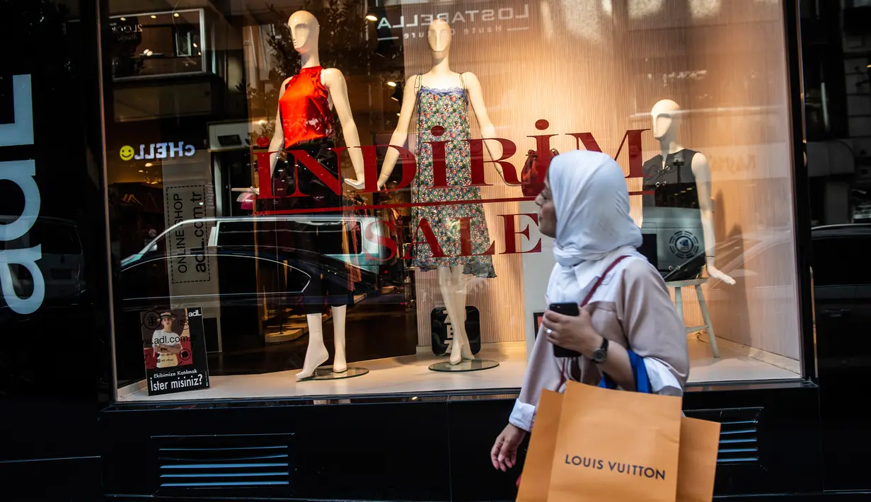 Seorang wanita memegang tas belanja Louis Vuitton di Istanbul pada 13 Agustus 2018. Di tengah kondisi lira yang terus melemah, wisatawan mancanegara justru menikmati berbelanja barang-barang mewah di Turki dengan harga yang sangat miring (AFP/Yasin AKGUL)