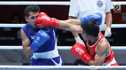 Petinju putra Indonesia, Sunan Agung Amoragam (kaus merah) melancarkan pukulan Mirazizbek Mirzakhalilov (Uzbekistan) pada semifinal bantam 56kg putra Asian Games 2018 di JIEXPO Kemayoran, Jumat (31/8). Amoragam kalah 0-5. (Liputan6.com/Helmi Fithriansyah)