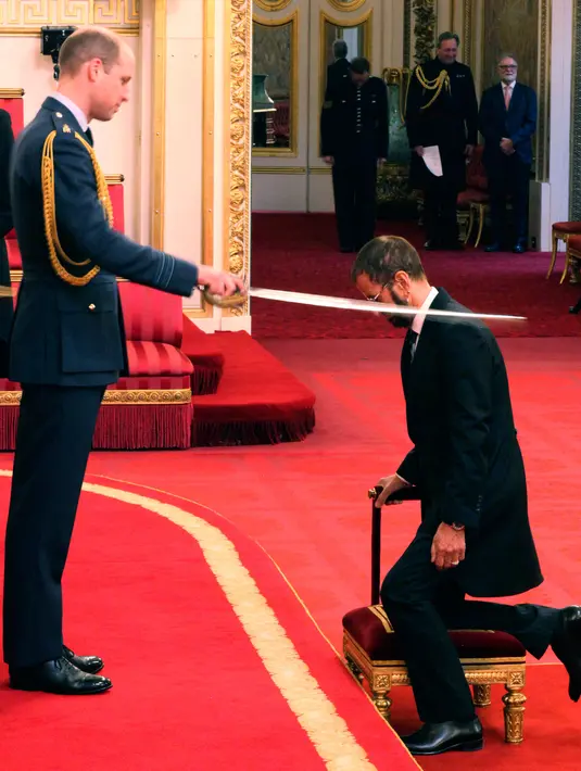 Ringo Starr saat menerima gelar kebangsawanan dari Pangeran William di Istana Buckingham, di London, Inggris (20/3). Ringgo diberi gelar 'Sir' atas jasanya dalam dunia musik. (Yui Mok / PA via AP)