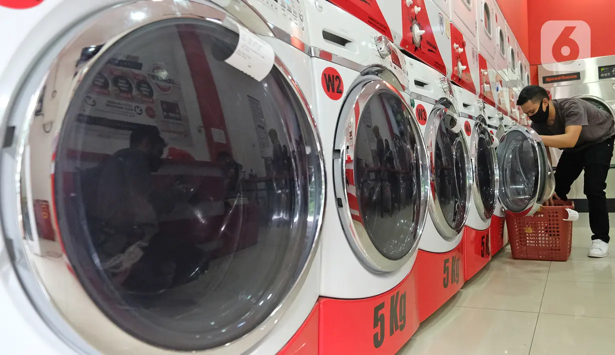 Pekerja memasukkan pakaian ke mesin cuci di gerai jasa layanan laundry, kawasan Kemang, Jakarta, Rabu (25/11/2020). Sejak tiga bulan terakhir omset mereka kembali membaik dan mengalami peningkatan sebesar 20 hingga 30 persen. (Liputan6.com/Herman Zakharia)