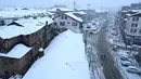 Orang-orang melintasi jalan yang tertutup salju di kota utama Kashmir, Srinagar, Kamis (7/11/2019). Srinagar menyambut salju pertama musim ini yang mulai turun. (Photo by Tauseef MUSTAFA / AFP)